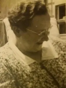 Sepiafoto einer älteren Frau mit Brille und lockigem Haar, den Blick gesenkt