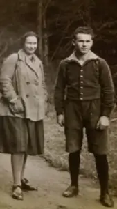 Historisches Foto: eine Frau im Mantel und ein junger Mann in Kniebundhose stehen auf einem Waldweg